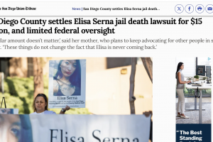 Paloma Serna, holds up a sign of her daughter, Elisa Serna, who died in jail in 2019, during a vigil and rally 